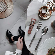 Dr PAWPAW Rich Mocha Balm tube on a marble table beside a mirror and cutlery